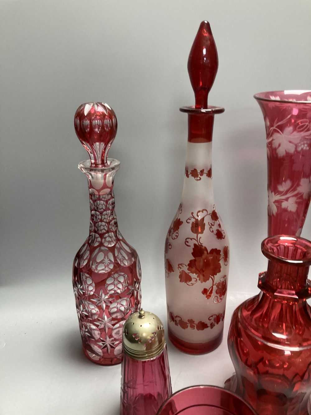 A collection of nine pieces of cranberry and ruby coloured glass, including a pair of decanters, two vases and a carafe and tumbler